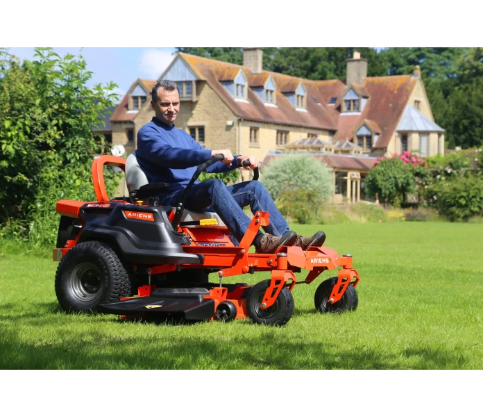 ariens ikon xd zero turn side view cutting grass with house in background scaled kuva